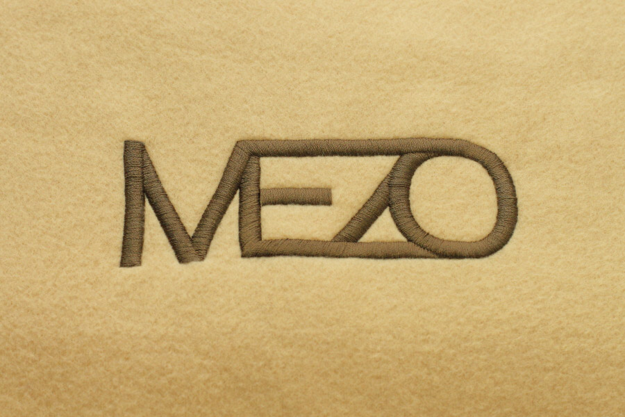 close-up photo of embroidery on a beige fleece lap blanket